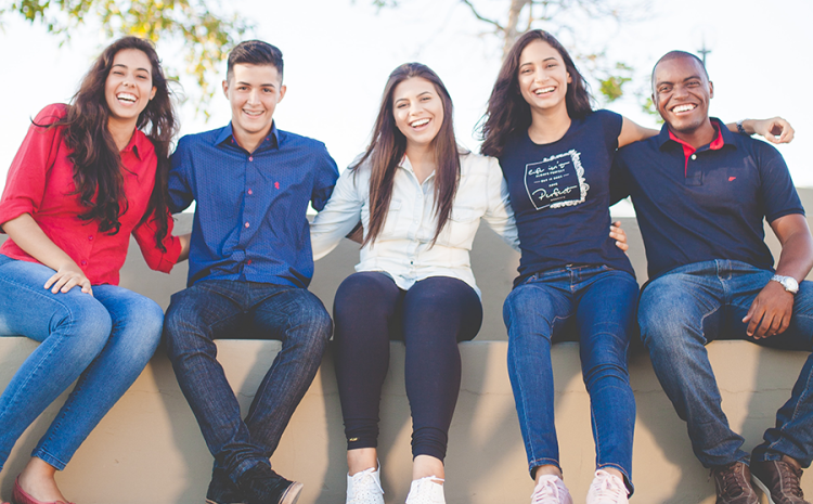 Group of five teens smiling and posing for picture