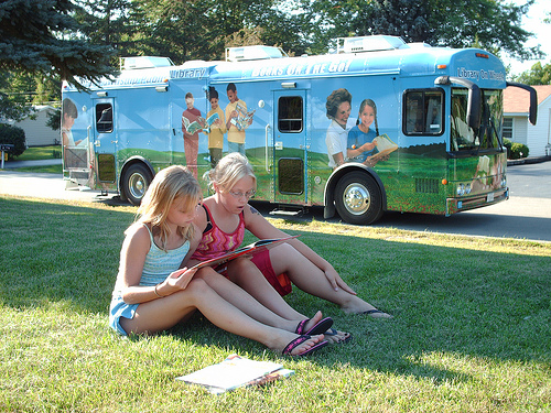 Two girls reading together in front of bookmobile