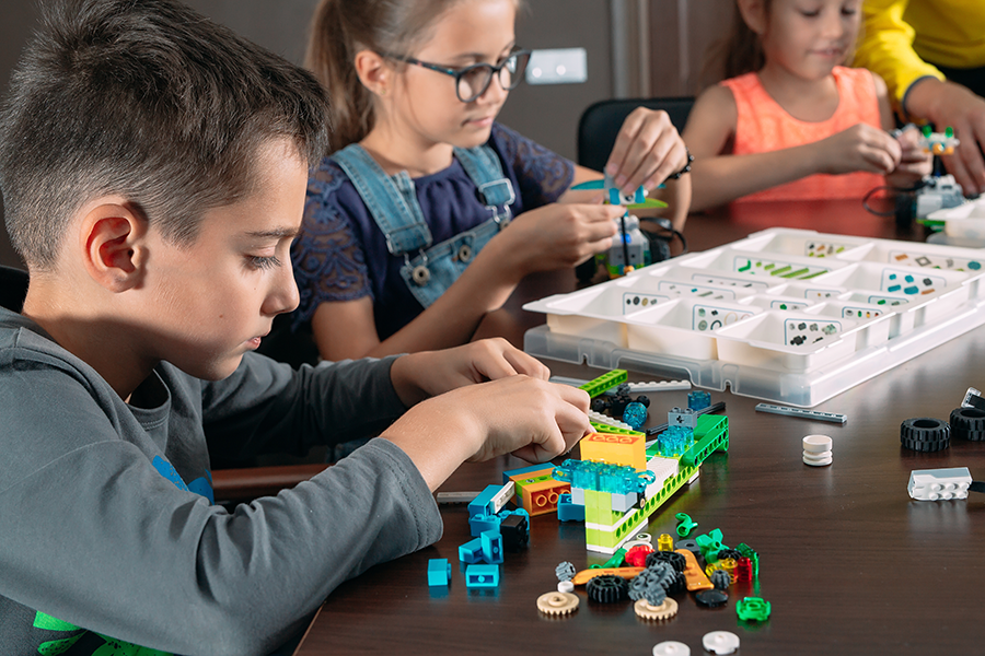 group of three children playing with Legos