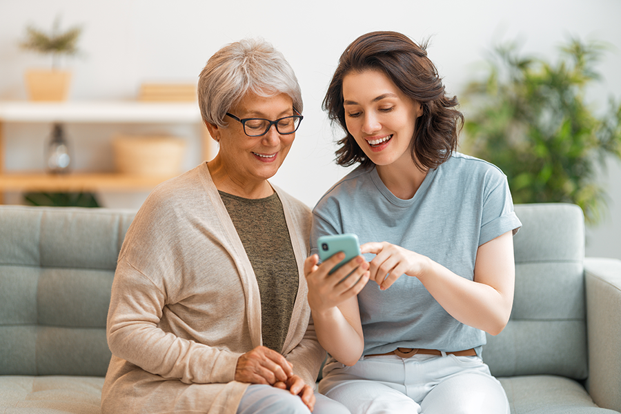 Younger woman helping senior woman with smartphone