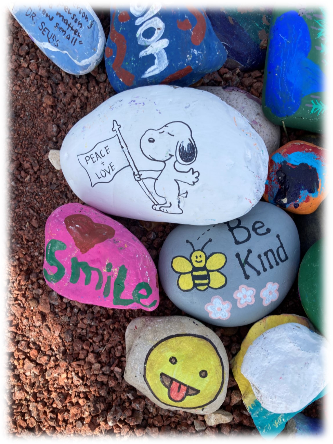 Rocks painted with Snoopy, an emoji, Be Kind with a bee, etc. 