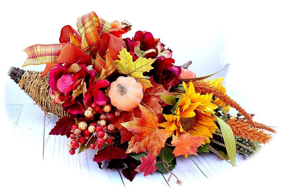 A woven cornucopia filled with Fall leaves and flowers, berry sprays, a mini pumpkin and a bow. 