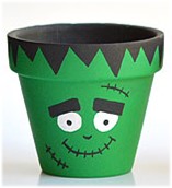 Clay pot painted green, black and white that looks like Frankenstein.
