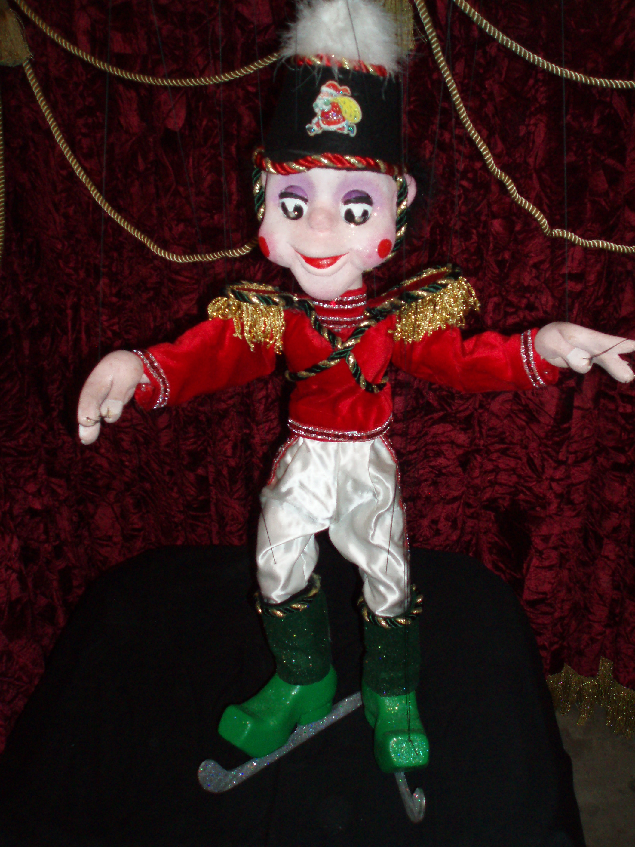 Soldier marionette puppet dressed in a red jacket, white slacks and green ice skates.