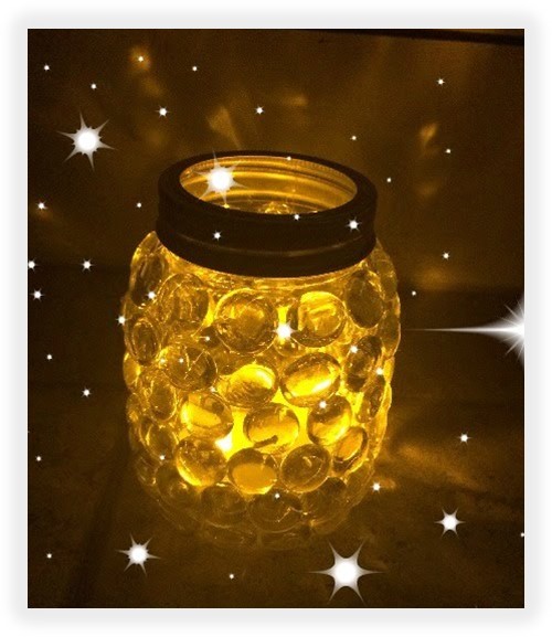Mason jar with clear gems glued on the outside and fairy lights inside the jar. 