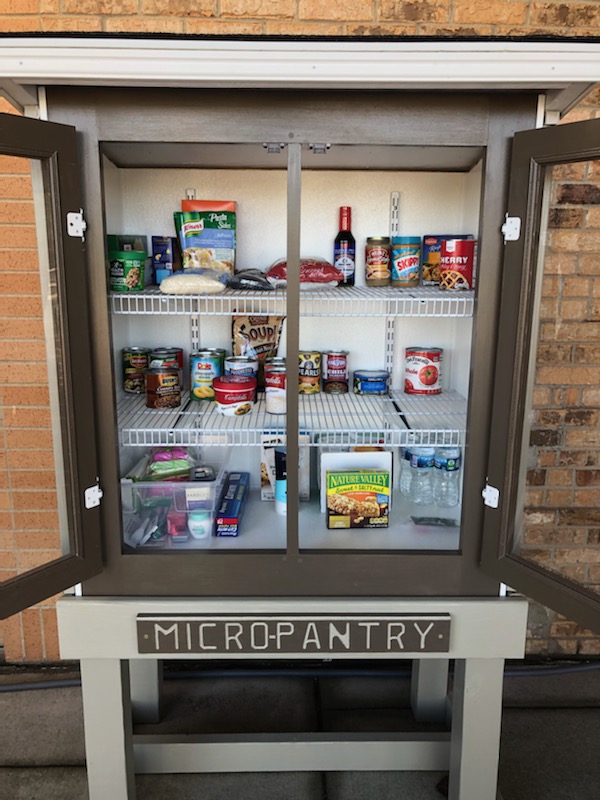 Micro pantry with its' doors open, Three shelves of food are inside. 