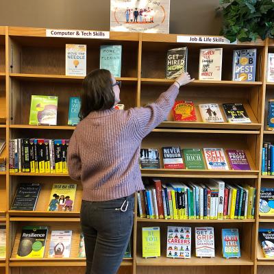 Person browsing library "Job & Life Skills" shelves