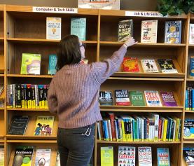 Person browsing library "Job & Life Skills" shelves
