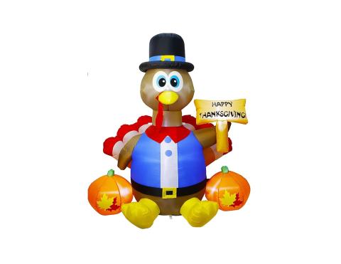 inflatable turkey dress in pilgrim clothes and hat, holding Happy Thanksgiving sign, sitting in the middle of 2 pumpkins