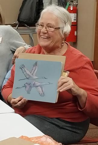 Smiling woman holding a piece of artwork. 