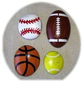 Four rocks painted as a baseball, football, basketball, and tennis ball.