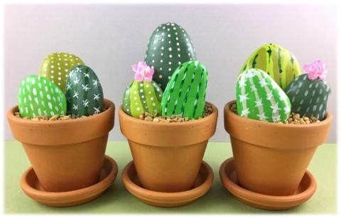 Three clay pots with rocks painted to look like cacti planted in pots.