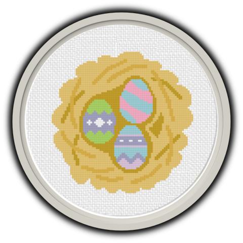 Gray frame with cross stitch light brown nest and three multicolored eggs in nest. 