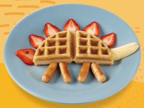 Blue plate with a dinosaur made out of waffles, sausages, banana and strawberries.