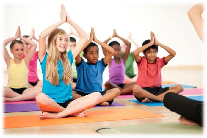 Tweens sitting on floor with legs crossed and hands clasped above their heads.