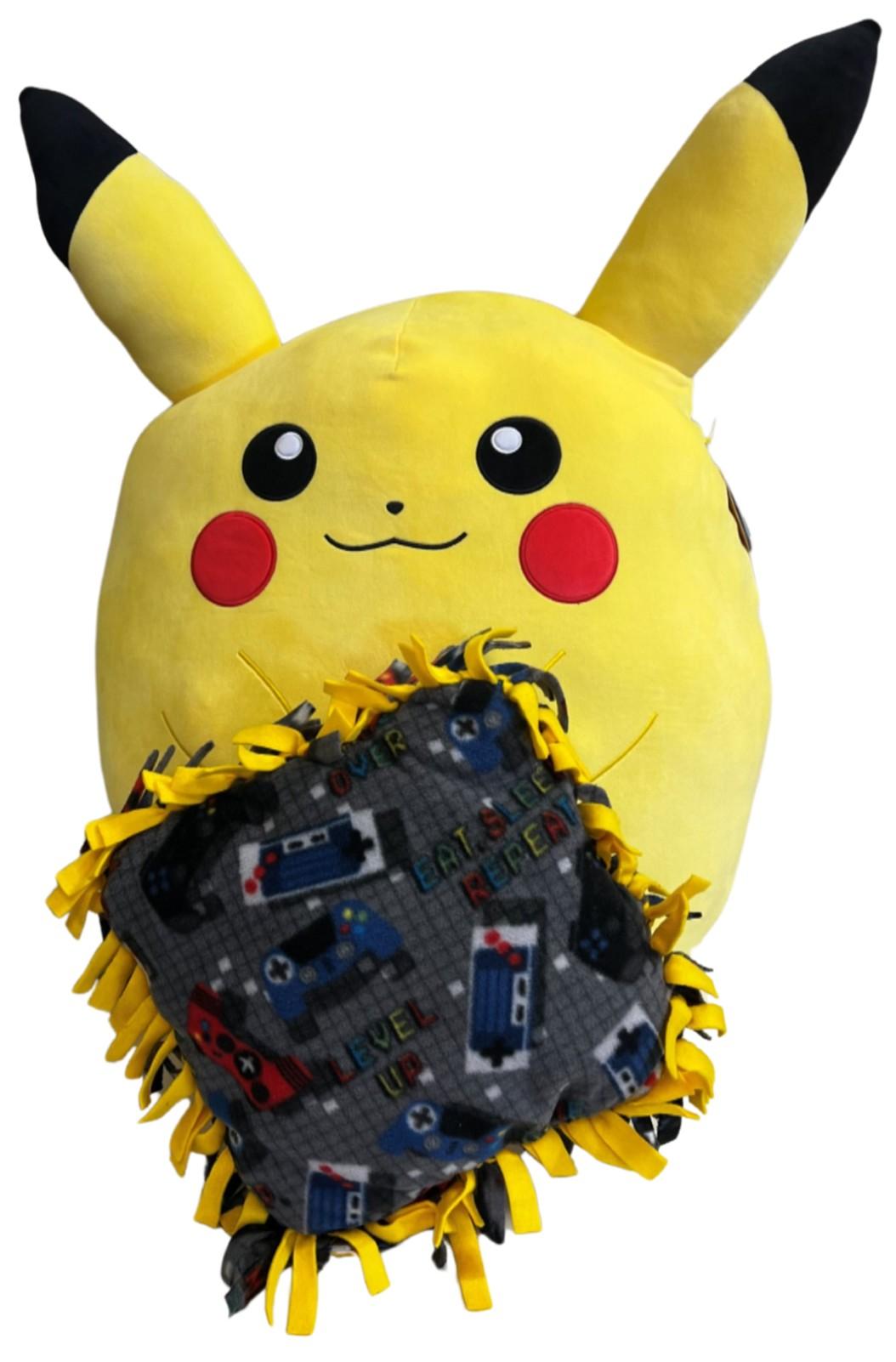 Yellow Pikachu holding a gaming controller print pillow with yellow and black knotted fringe. 