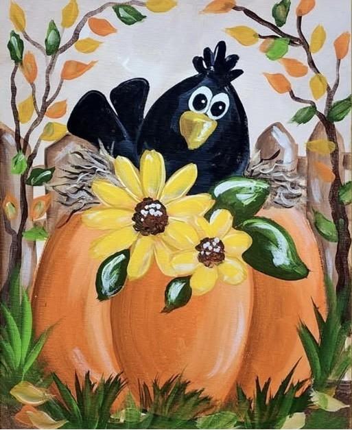 Large b;ack crow perched on top of an orange pumpkin with two large yellow sunflowers.